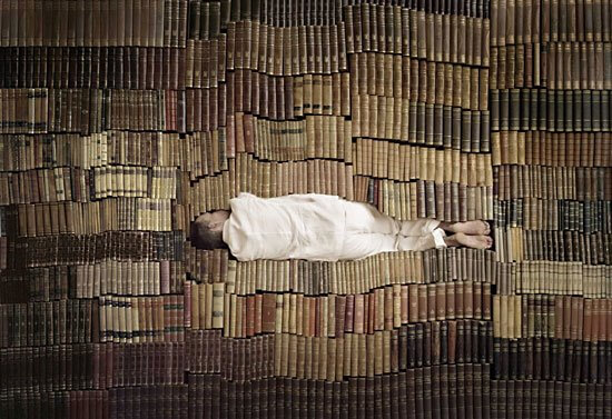 Persona durmiendo en pila de libros
